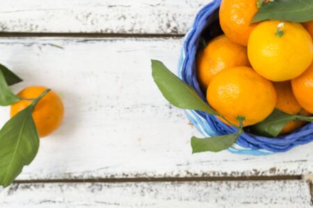 Tangerines , oranges, clementines, citrus fruits, with green leaves lie in a wicker basket on a wooden background with copy space. View from above. Christmas concept.の写真素材