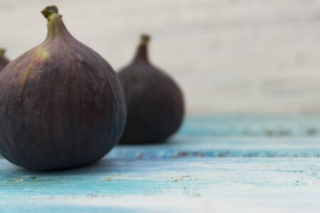 Three fresh figs on a wooden white table. Arranged in a row. The concept of urge.の写真素材