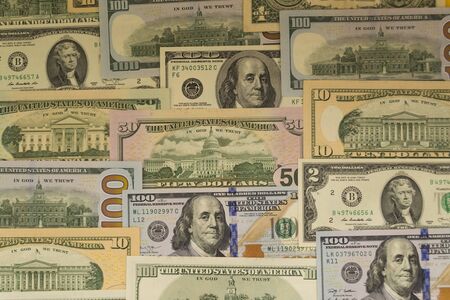 Banknotes of one hundred dollars and another denomination, lie in neat rows as a background. Business concept, currency exchange.の写真素材