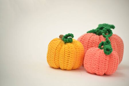 Autumn white background with knitted pumpkins. Side view of knitted pumpkins of different sizes. Happy Thanksgiving Autumn Background. Autumn concept, there is a place for text.の写真素材