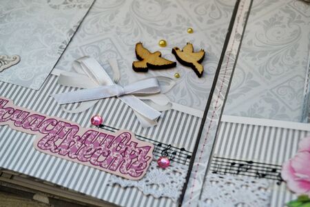 Scrapbooking handmade photo album. Diy. Top view on table with elements for scrapbooking, cut paper, die cuts, paper flowers, ribbons,embossing. Women hobby. Wedding album. The concept of handicraft, wedding. The inscription in Russian Happy together.の写真素材