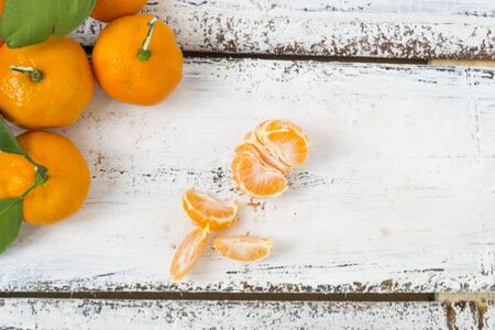 A large mass of tangerines lies on a white wooden background. A row of tangerines peeled on slices lies. There is a place for text. Christmas concept.の写真素材