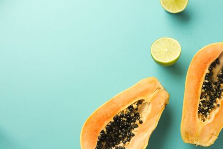 Summer composition. Tropical lime and papaya fruit cut in half lie on a blue background. Summer...