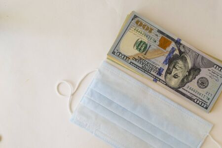 protective mask, and dollar bills on a white background. The concept of expensive medicine. Pharmaceutical industry and health insurance. There is a place for text.の写真素材