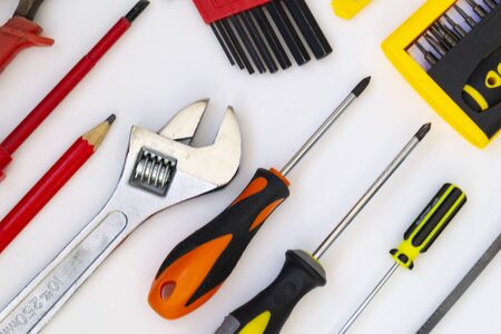 Construction tools lie on a white background. Screwdrivers, a saw, a gas wrench, a pencil, pliers, a...