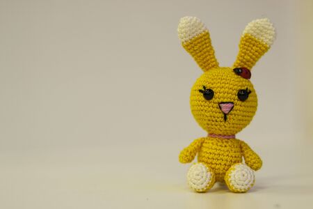 Amigurumi yellow hare sitting on a white background. Needlework concept. There is a place for textの写真素材
