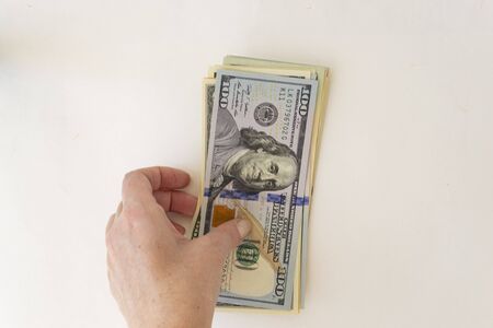Hold one hundred dollars in hand on a white background. Concept of counting money.の写真素材