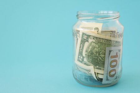 Money in a liter jar on a blue background. American dollars are in the piggy bank. The concept of business, finance. There is a place for text.の写真素材