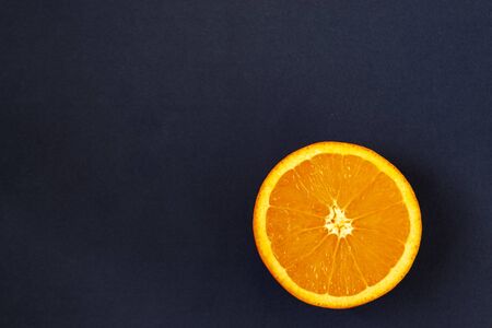 Fresh sliced orange lies on a black background. Tropical fruits on a chalk board flatlay. Copy spaceの写真素材