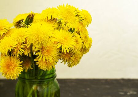 Bouquet of yellow flowers in a glass green jar. Spring yellow dandelionの写真素材