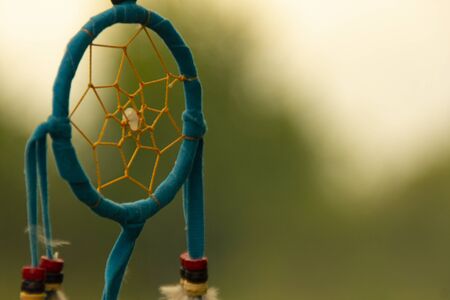 Dreamcatcher close-up on a background of green grass and blue sky. Blurred background. Copy spaceの写真素材