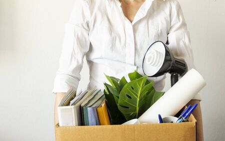 lose job concept. Hand holds box of fired worker. In a box they lay documents, folders, a flower,...