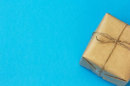 Craft paper wrapped gift box craft rope bow ribbon on a blue background, top view. Mockup for Father's Day celebration. Copy space.の写真素材