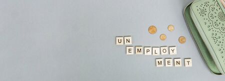 Green wallet with scattered euro coins on a gray background. Inscription unemployment. Banner. Last money, poverty, job loss, saving concept. Flat lay, close up. Copy spaceの写真素材