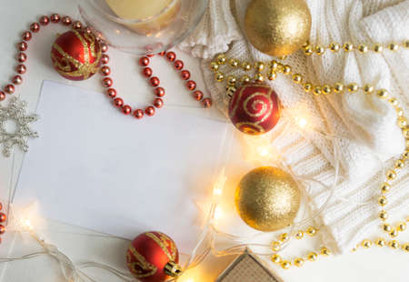 Christmas art card. Snowflakes and Christmas tree gold and red balls, a white jacket, and garlands lie around a blank sheet. There is a place for text.の写真素材
