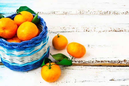 Citrus tangerines lie in a white and blue basket on a white wooden background. Christmas concept. Copy of space.の写真素材