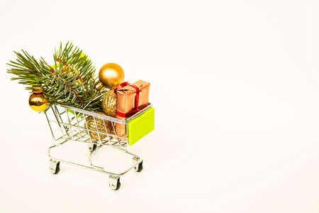 Grocery basket with golden gift boxes and Christmas balls, sprig of Christmas tree on white background banner with copy space. Xmas sale. Christmas shopping online. Winter holiday sales and discounts, seasonal sales, Black Friday, Christmas, discounts and online shopping.の写真素材