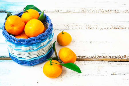 Citrus tangerines lie in a white and blue basket on a white wooden background. Christmas concept. Copy of space.の写真素材