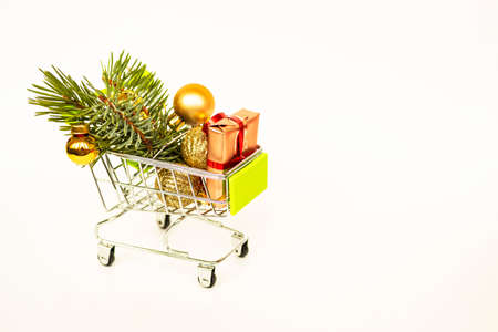 Grocery basket with golden gift boxes and Christmas balls, sprig of Christmas tree on white background banner with copy space. Xmas sale. Christmas shopping online. Winter holiday sales and discounts, seasonal sales, Black Friday, Christmas, discounts and online shopping.の写真素材