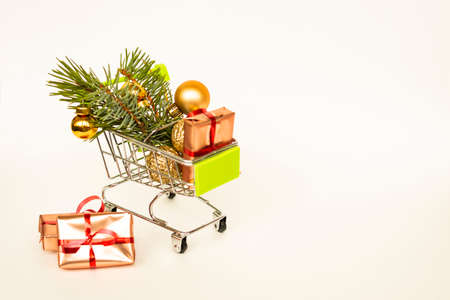 Grocery basket with golden gift boxes and Christmas balls, sprig of Christmas tree on white background banner with copy space. Xmas sale. Christmas shopping online. Winter holiday sales and discounts, seasonal sales, Black Friday, Christmas, discounts and online shopping.の写真素材