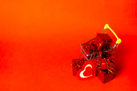 Shopping trolley with gift box, love hearts and cope space on red background. St. Valentine's Day shopping and sale.の写真素材