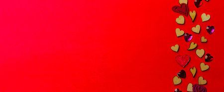 Valentine's day background from wooden and crystal hearts on a red backdrop. Saint valentine long banner. Love and wedding concept.の写真素材