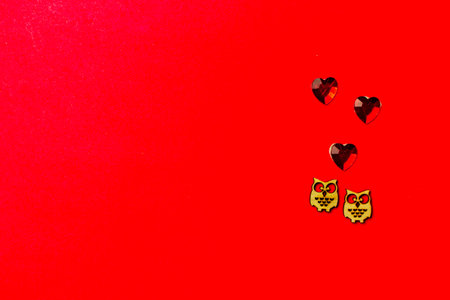 Two wooden owl birds in love, and hearts on a red background. Copy space. Valentine's day and wedding. Love postcardの写真素材