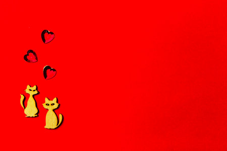 Two enamored animals, wooden cats with a crystal heart on a red background. Copy space. Valentine's Day and wedding concept.の写真素材