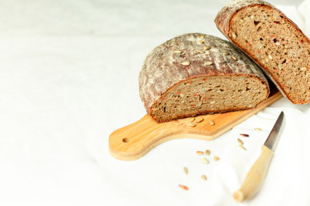 Black sliced bread on a wooden board with a knife against a white background. Blurred background....