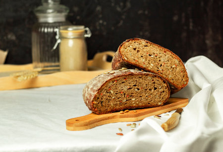 Black sliced bread on a wooden board with a knife against a white background. Blurred background. Copy space.の写真素材