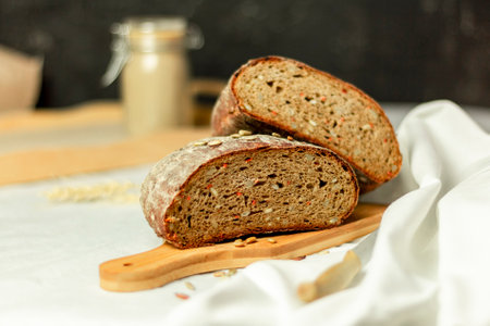Black sliced bread on a wooden board with a knife against a white background. Blurred background. Copy space.の写真素材