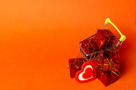 Shopping trolley with gift box, love hearts and cope space on red background. St. Valentine's Day shopping and sale.の写真素材