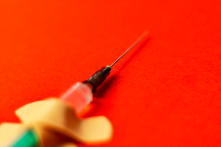 Medical syringe hooked with a plaster on a red background. Vaccination concept. No covid vaccineの写真素材