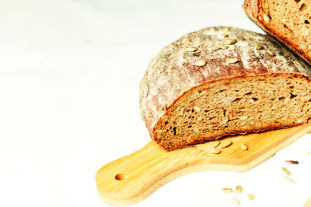 Black sliced bread on a wooden board with a knife against a white background. Blurred background. Copy space.の写真素材