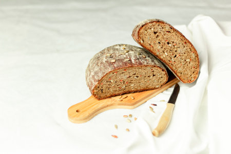 Black sliced bread on a wooden board with a knife against a white background. Blurred background. Copy space.の写真素材