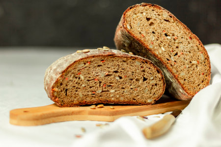 Black sliced bread on a wooden board with a knife against a white background. Blurred background. Copy space.の写真素材
