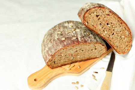 Black sliced bread on a wooden board with a knife against a white background. Blurred background. Copy space.の写真素材