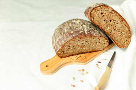 Black sliced bread on a wooden board with a knife against a white background. Blurred background. Copy space.の写真素材