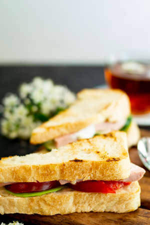 English sandwiches. Filling with tomato, dill and butter. The shape is triangular. A cup of tea is visible in the background. Blurred background. Copy space.の写真素材