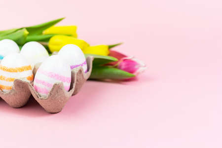 Easter painted eggs with tulips on a pink background. Copy space. Easter celebration conceptの写真素材