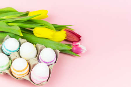 Easter painted eggs with tulips on a pink background. Copy space. Easter celebration concept