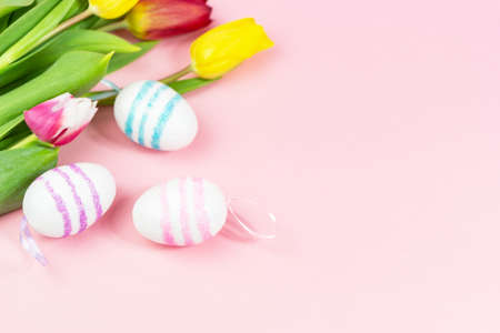Easter painted eggs with tulips on a pink background. Copy space. Easter celebration conceptの写真素材