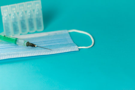 Medical vials for injection, syringe for injection, mask gloves on a blue background. Admission vaccination, flu shot.の写真素材