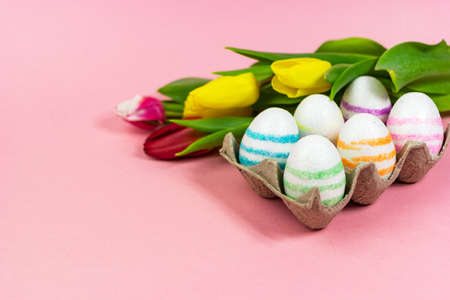 Easter painted eggs with tulips on a pink background. Copy space. Easter celebration conceptの写真素材