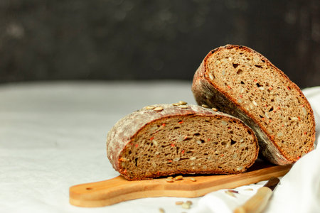 Black sliced bread on a wooden board with a knife against a white background. Blurred background. Copy space.の写真素材
