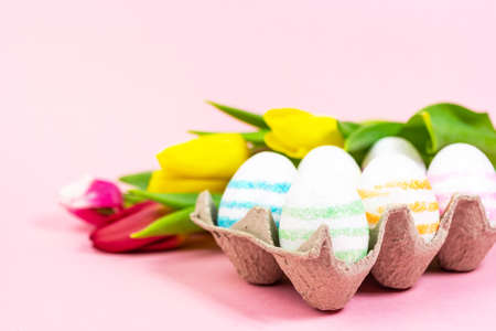 Easter painted eggs with tulips on a pink background. Copy space. Easter celebration conceptの写真素材