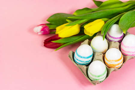 Easter painted eggs with tulips on a pink background. Copy space. Easter celebration conceptの写真素材