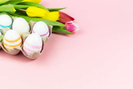 Easter painted eggs with tulips on a pink background. Copy space. Easter celebration conceptの写真素材