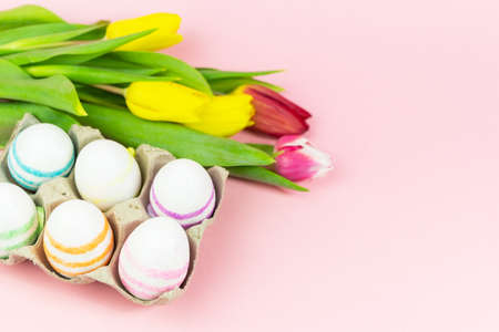 Easter painted eggs with tulips on a pink background. Copy space. Easter celebration conceptの写真素材