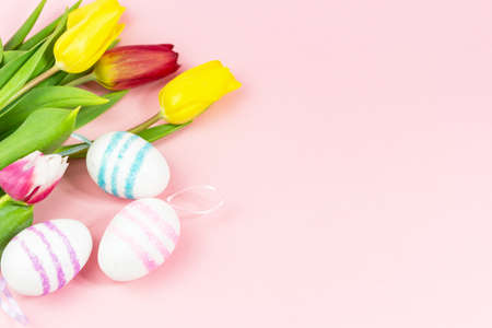 Easter painted eggs with tulips on a pink background. Copy space. Easter celebration conceptの写真素材